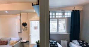Ein Zimmer mit einem Bett, einem kleinen Tisch, einem Stuhl und einem Fenster mit Blick nach draußen.