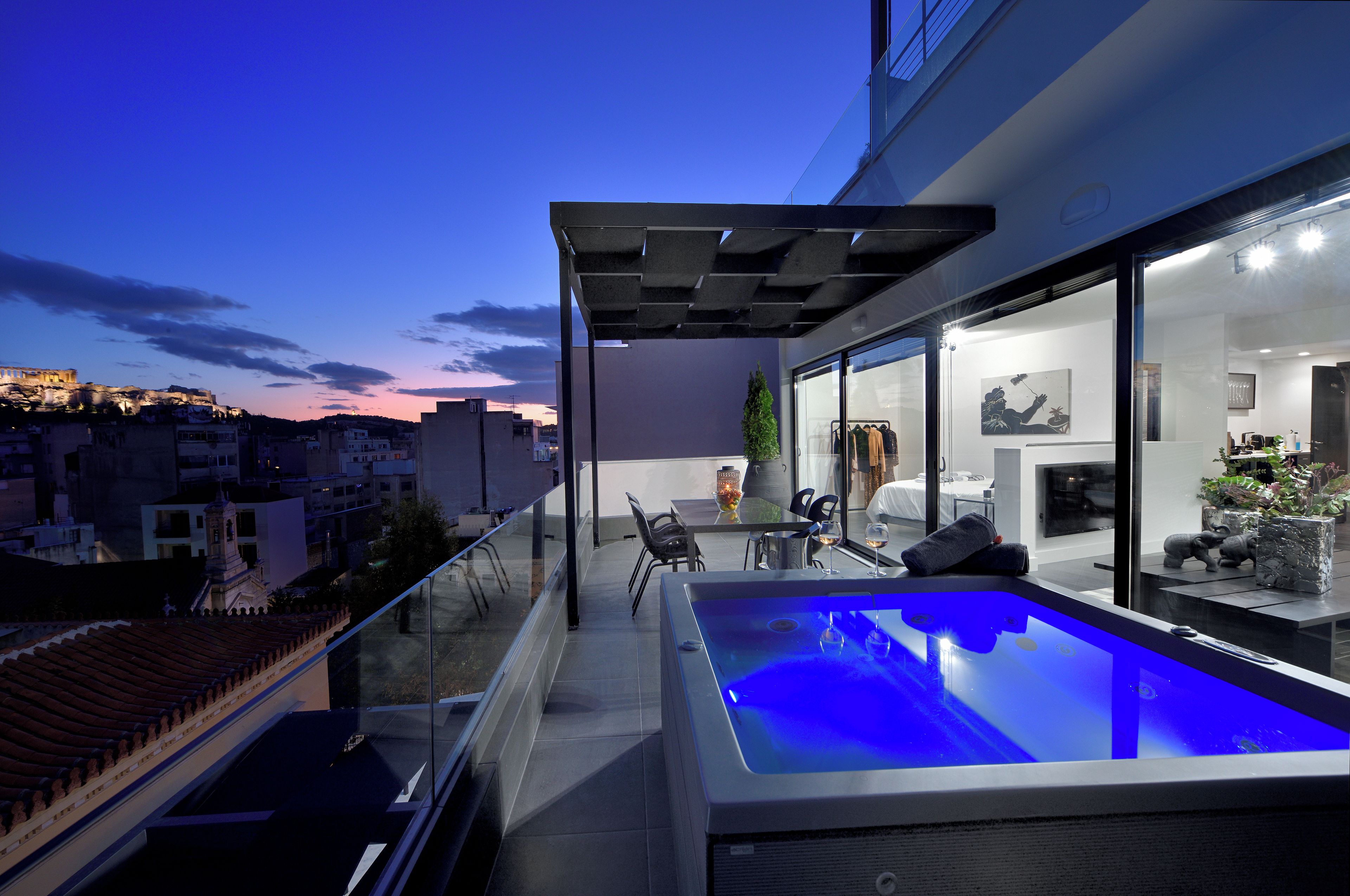 A rooftop terrace with a swimming pool, outdoor seating, and a view of the cityscape.