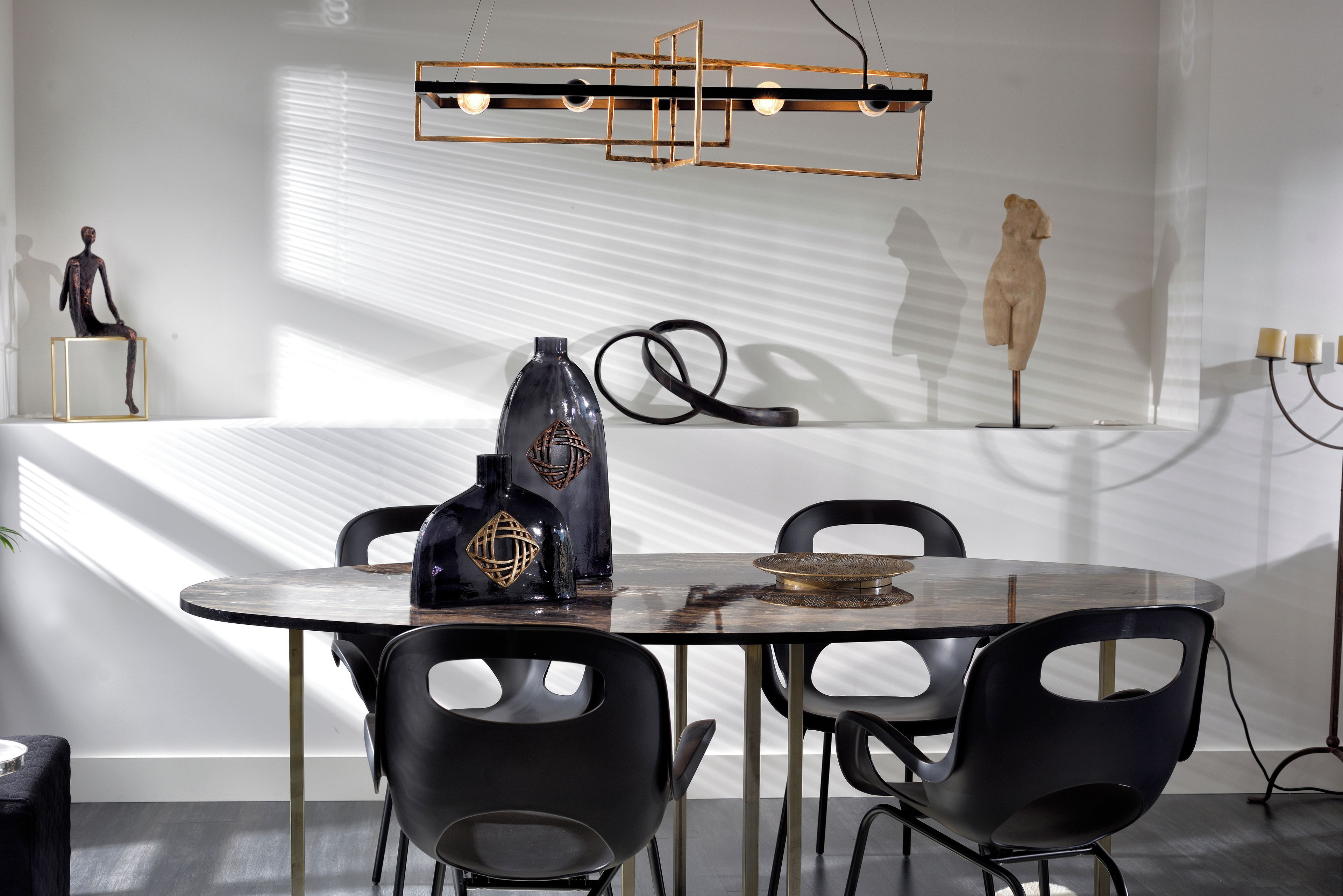 Un espace repas moderne avec une table ronde, des chaises noires et un vase décoratif.