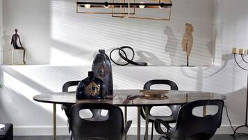 Un espace repas moderne avec une table ronde, des chaises noires et un vase décoratif.