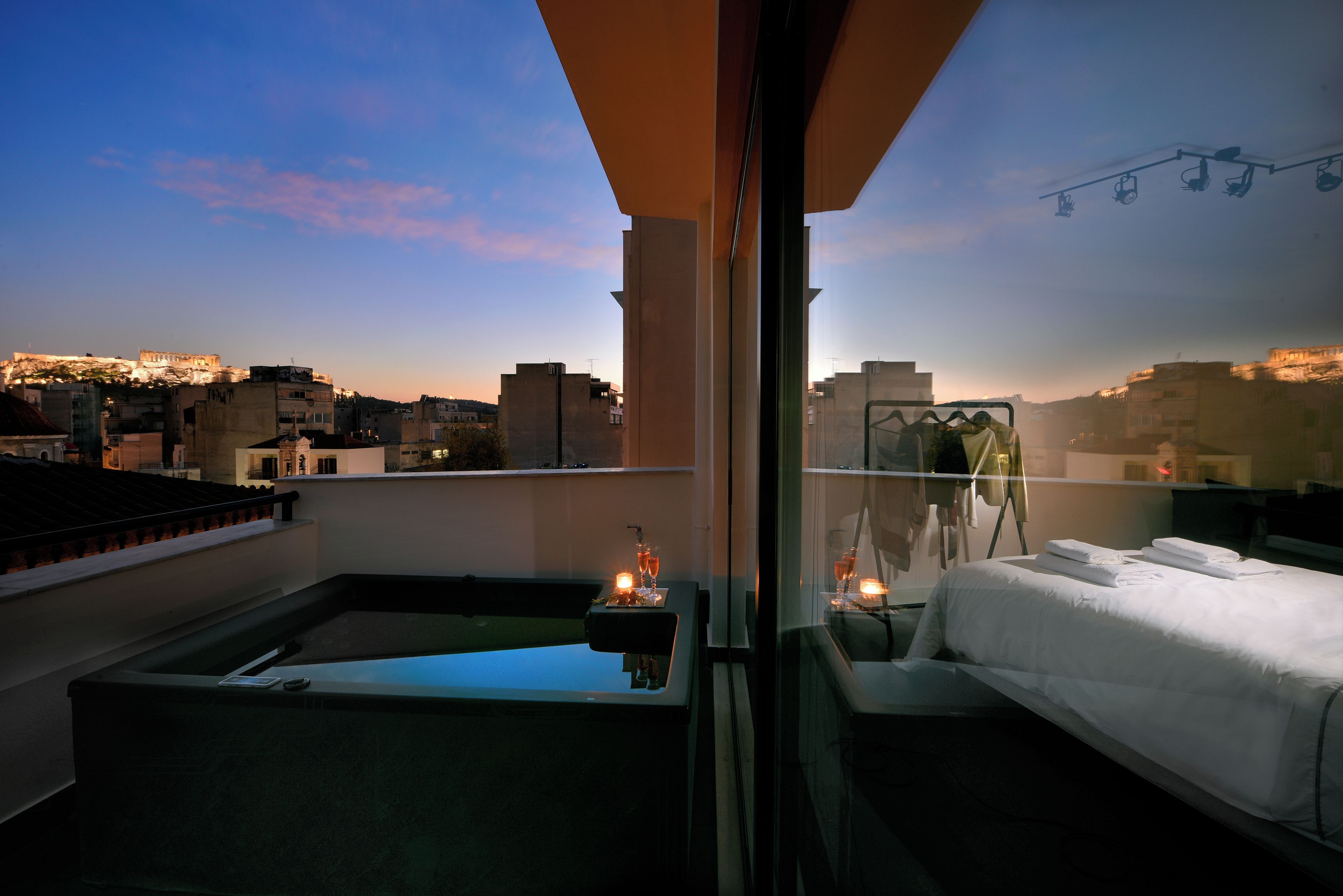 Une terrasse sur le toit avec une piscine, un lit et une vue sur la ville au crépuscule.