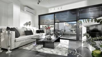 Un salon moderne avec un canapé blanc, une table basse et une grande fenêtre équipée de stores.