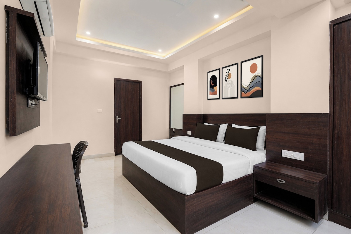 Quarto moderno com uma cama grande, mesas de cabeceira, escrivaninha e obras de arte na parede.