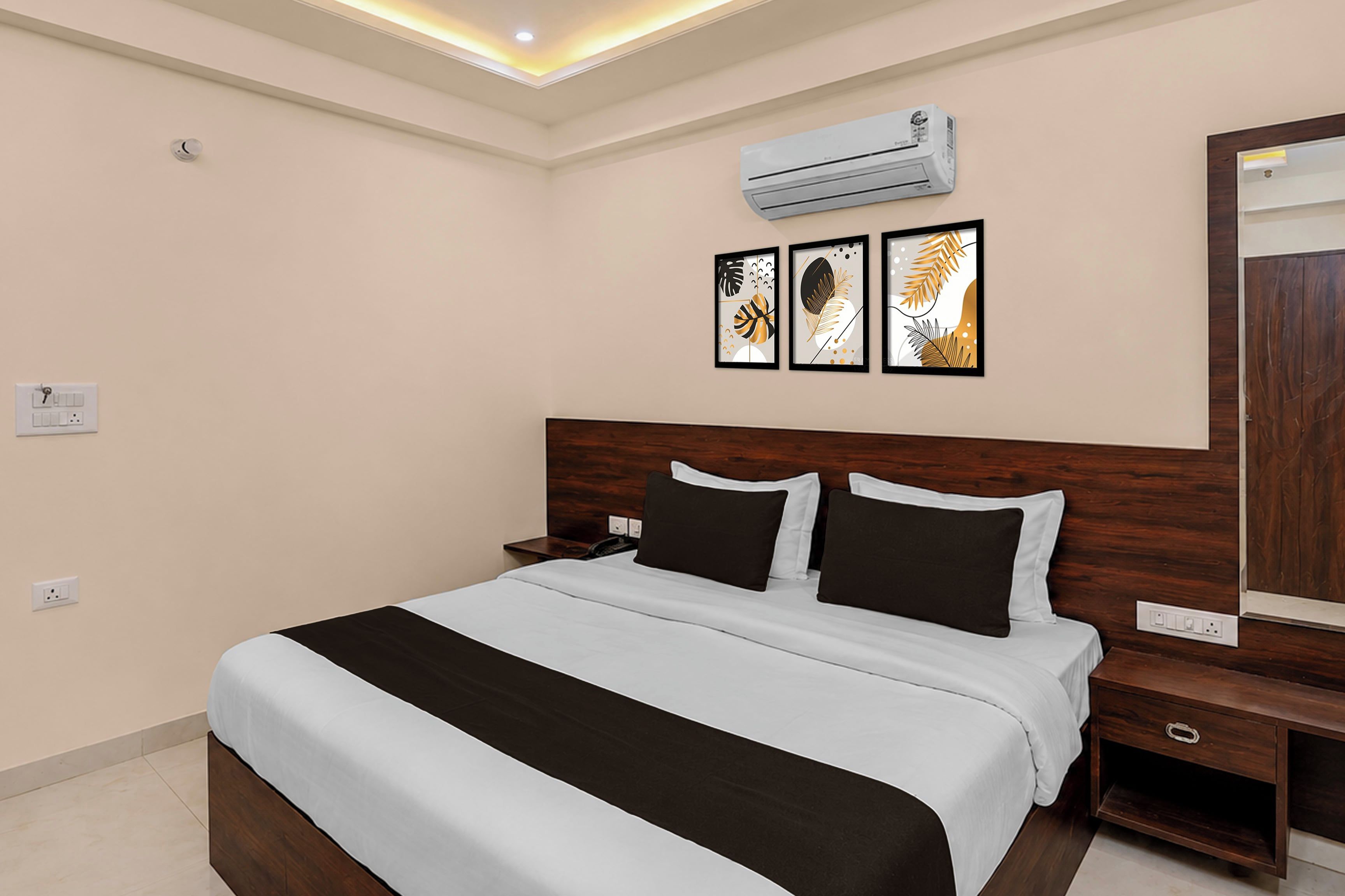 Habitación de hotel con cama, mesitas de noche, equipo de aire acondicionado y una obra de arte en la pared.