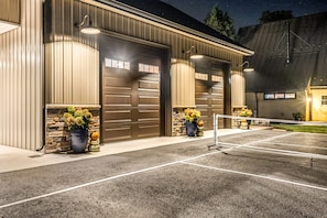 A building with multiple garage doors, a paved parking area, and outdoor lighting.