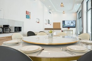 A modern dining area with a round table, chairs, and a television mounted on the wall. - Villa C | 6BR Private Pool | Central Pattaya (Pattaya City)