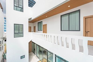 Hotelinterieur met meerdere niveaus, glazen balustrades, houten balken en grote ramen.