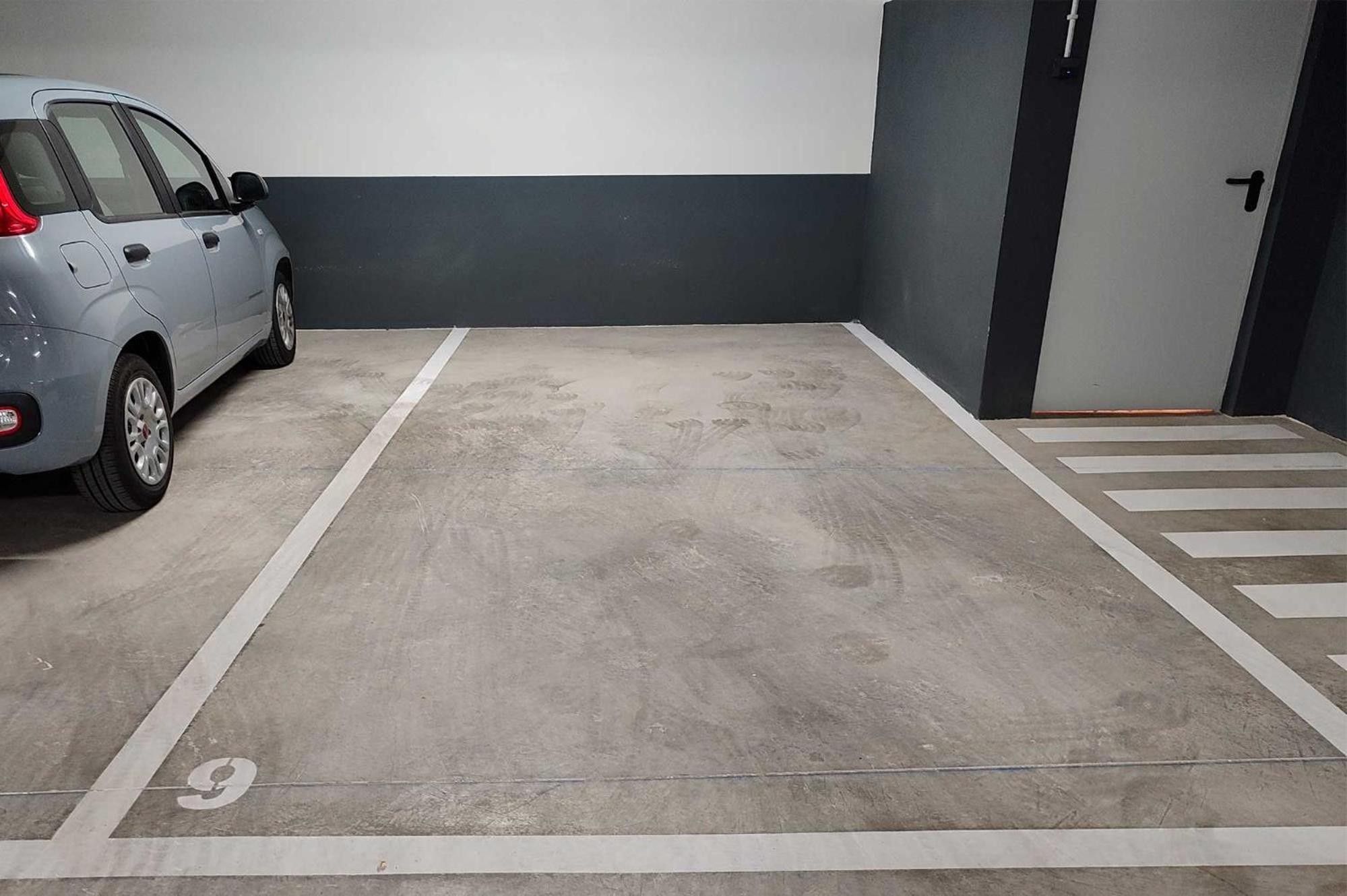 A parking area with a car parked in a designated space marked with the number 9.