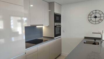 Una cocina moderna con horno integrado, microondas y un lavaplatos de acero inoxidable.