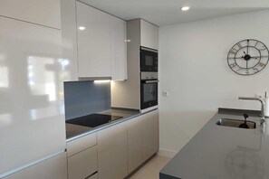 A modern kitchen with a built-in oven, microwave, and a stainless steel sink. - Apartment 'Pure South' with Mediterranean Views (Manilva)