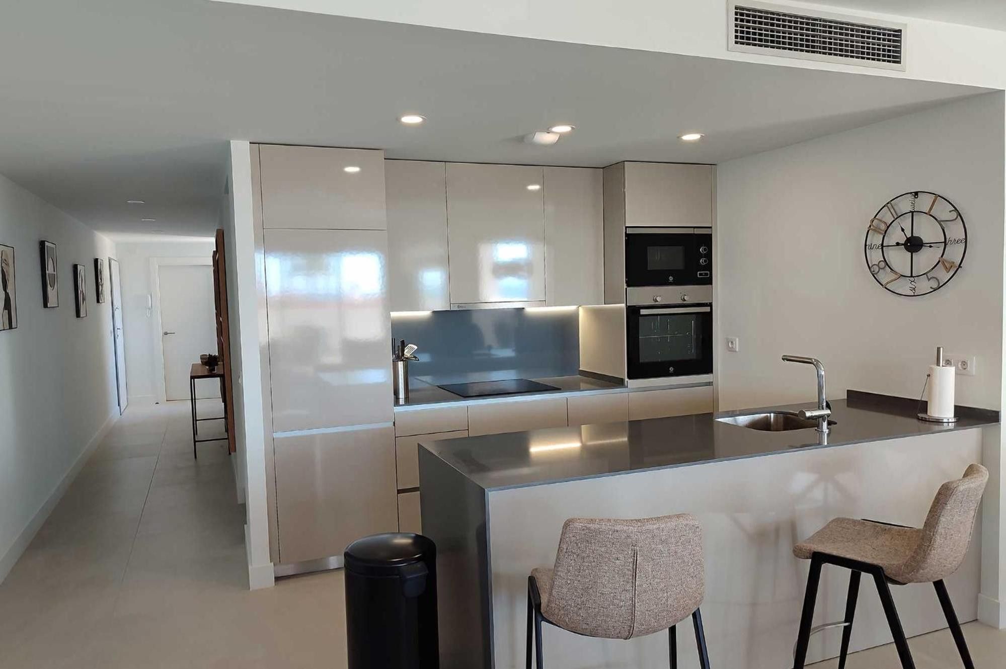 Une cuisine moderne dotée d’un îlot central, d’appareils électroménagers intégrés et d’un design minimaliste.