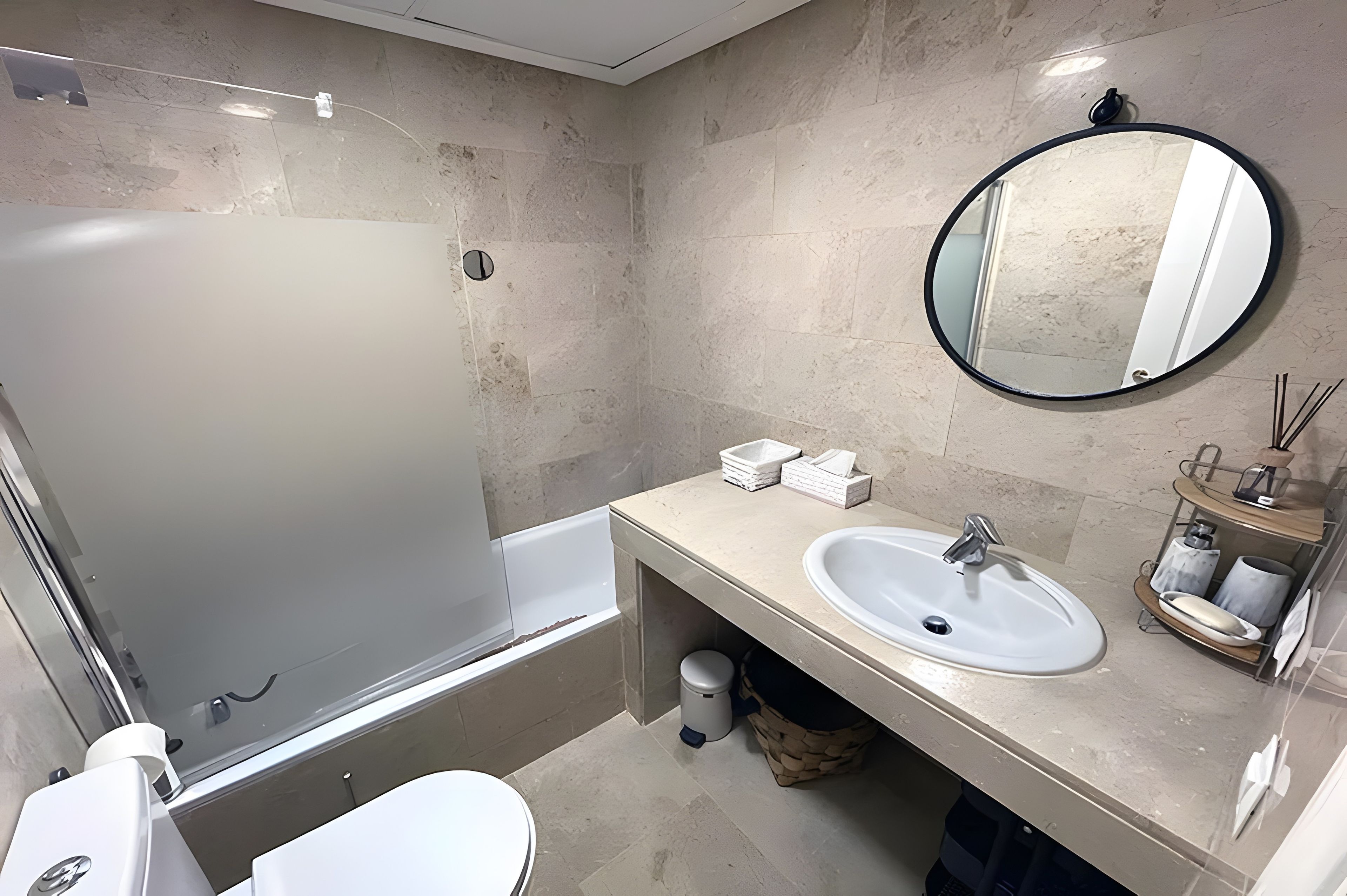 A bathroom with a bathtub, a sink, a toilet, and a mirror.