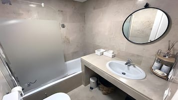 A bathroom with a bathtub, a sink, a toilet, and a mirror.