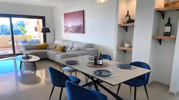 Ein modernes Wohnzimmer mit Essbereich, einer Couch, einem Couchtisch und einem Esstisch mit Stühlen.