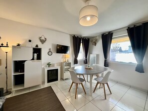 Ein modernes Wohnzimmer mit Esstisch, Stühlen, Fernseher und Kamin.