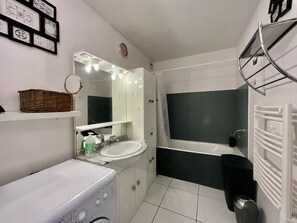 Ein modernes Badezimmer mit Waschmaschine, Waschtisch und Spiegel sowie einer Badewanne.