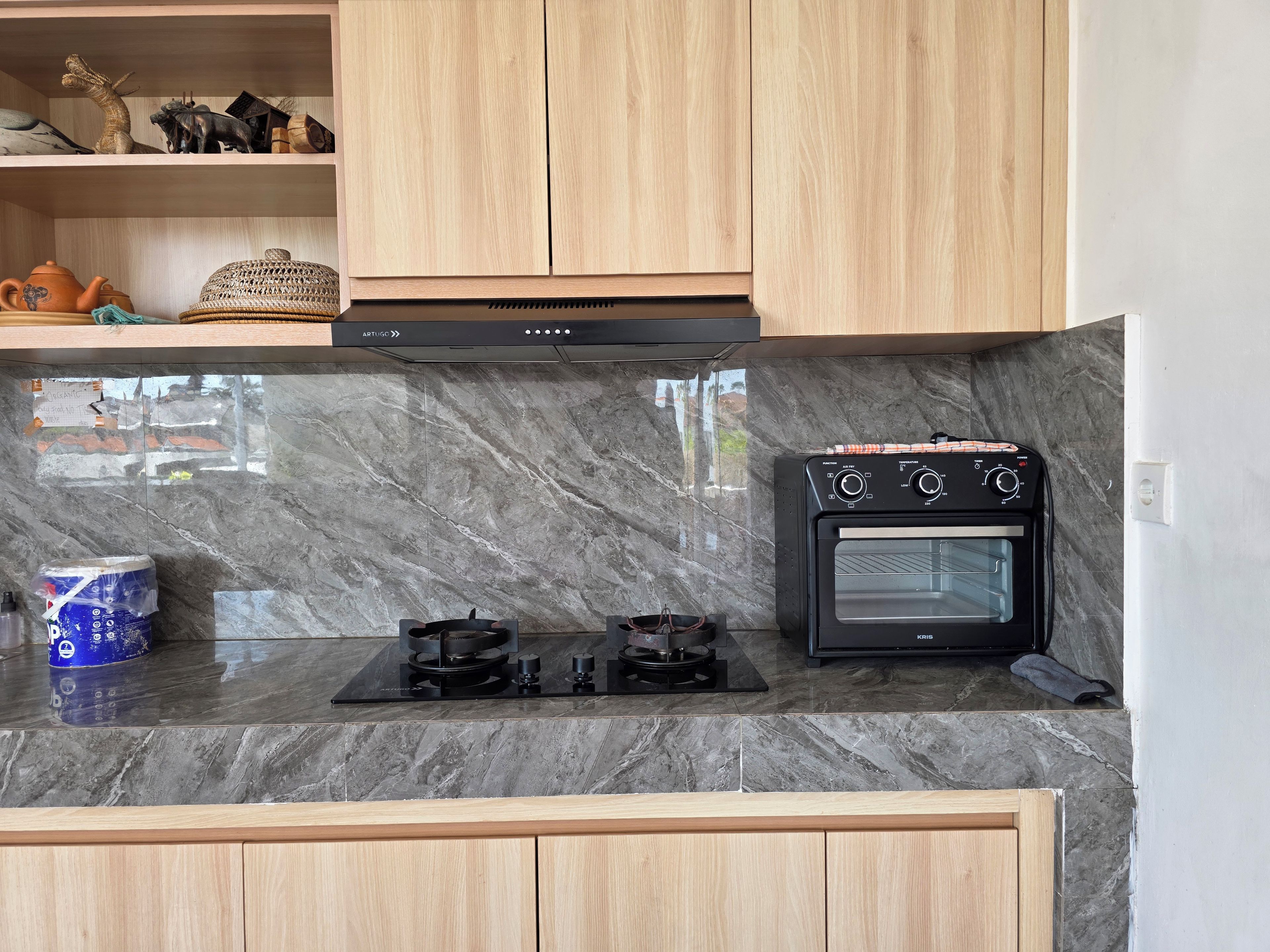 A kitchen with a marble countertop, a black oven, and wooden cabinets.
