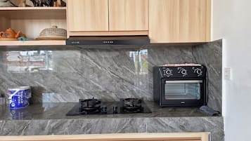 A kitchen with a marble countertop, a black oven, and wooden cabinets.