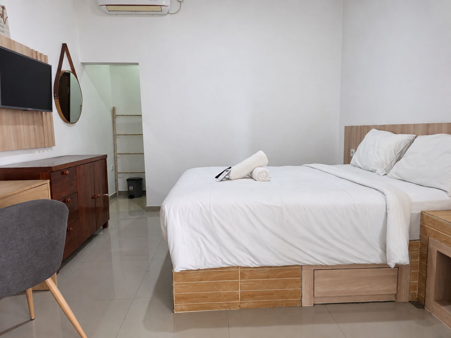 Una habitación de hotel moderna con cama, escritorio, silla y televisor.