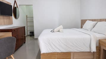 Een moderne hotelkamer met een bed, een bureau, een stoel en een televisie.