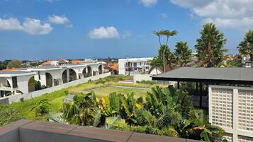 A residential area with white buildings, a grassy courtyard, and tropical vegetation.