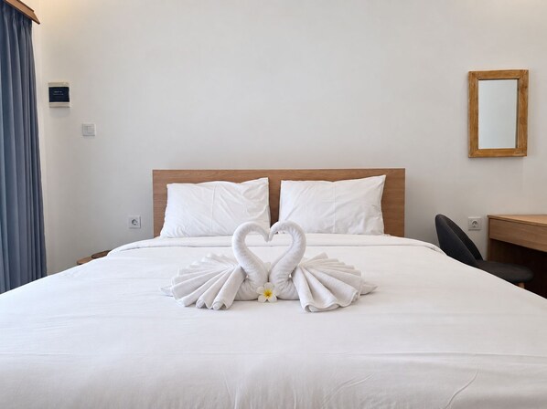 Habitación de hotel con una cama, cabecera de madera, escritorio y espejo.