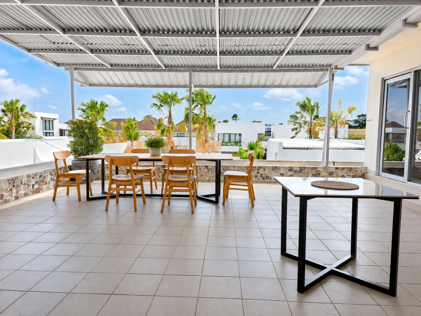 Un patio exterior con un área de estar techada, una mesa y sillas.