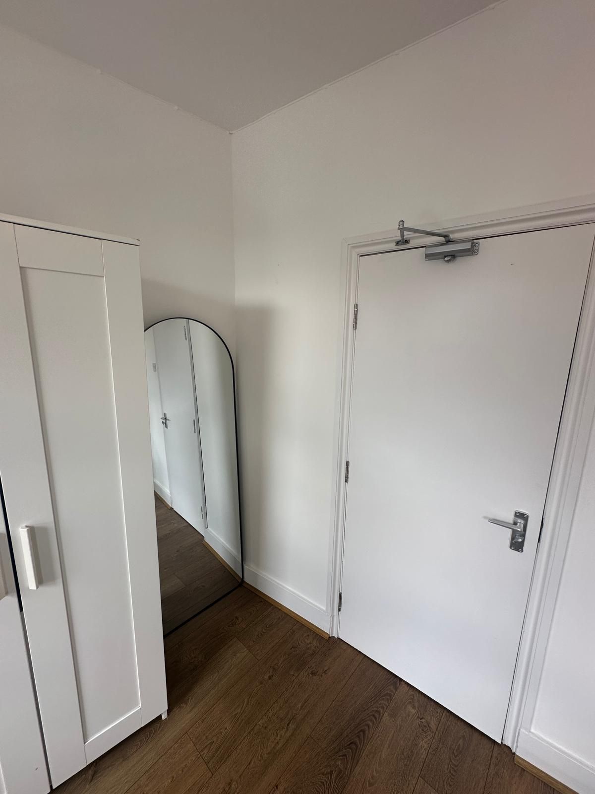 A hallway with a white door, a white wardrobe, and a white cabinet.