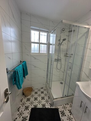 A bathroom with a glass-enclosed shower, a window, and a towel rack with towels. - Private Room with Private Kitchen & Bathroom (London)