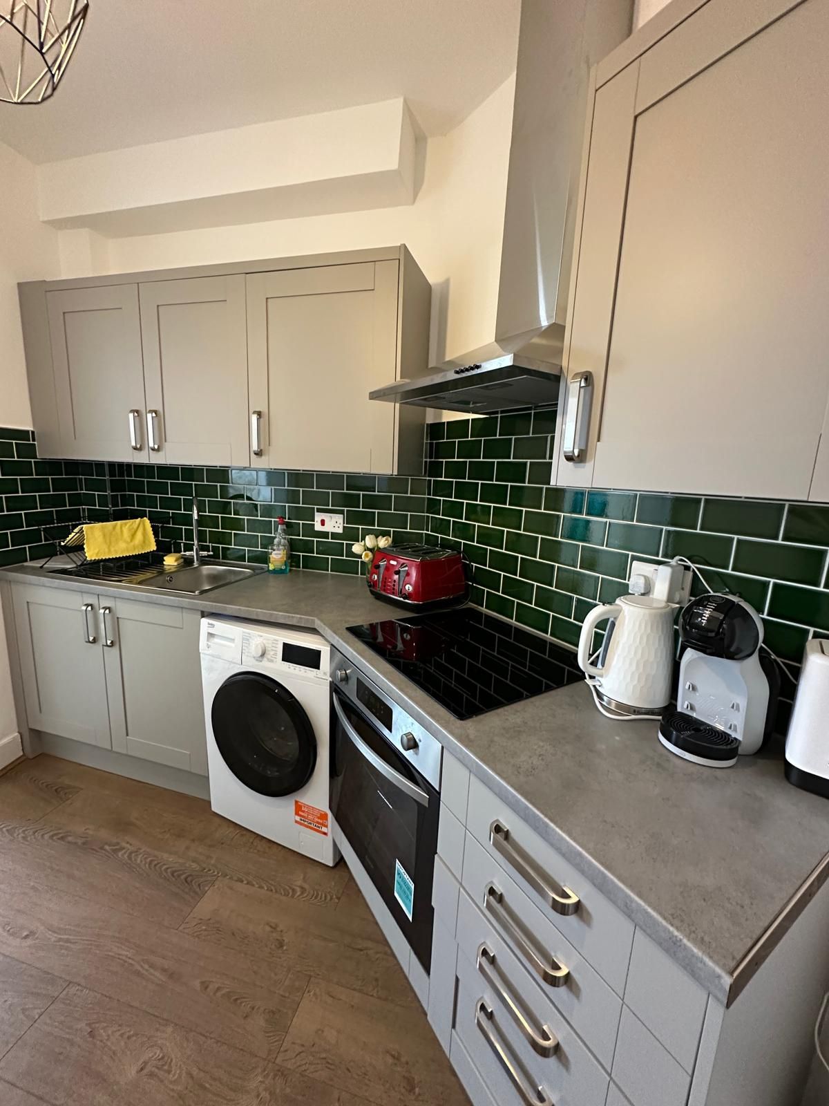 A compact kitchen with a washing machine, a coffee maker, and a toaster.