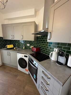 A compact kitchen with a washing machine, a coffee maker, and a toaster. - Private Room with Private Kitchen & Bathroom (London)