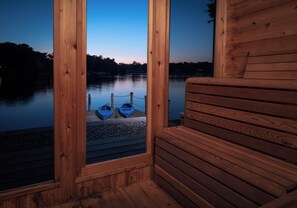 Eine Holzblockhütte mit Blick auf einen stillen See und angestoßenen Kajaks.