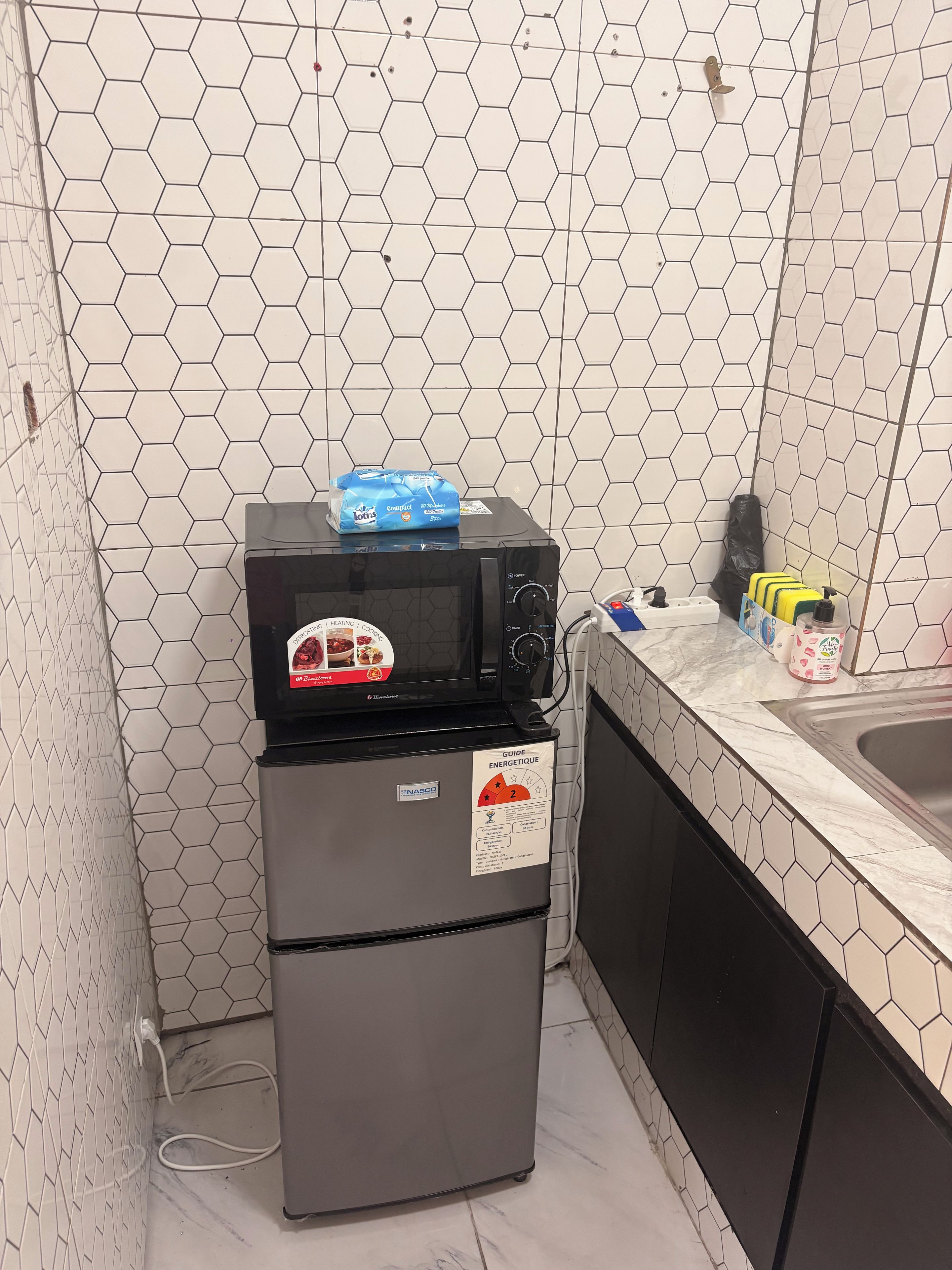 A compact kitchen with a microwave, a refrigerator, and a sink.