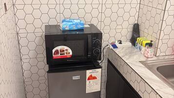 A compact kitchen with a microwave, a refrigerator, and a sink.