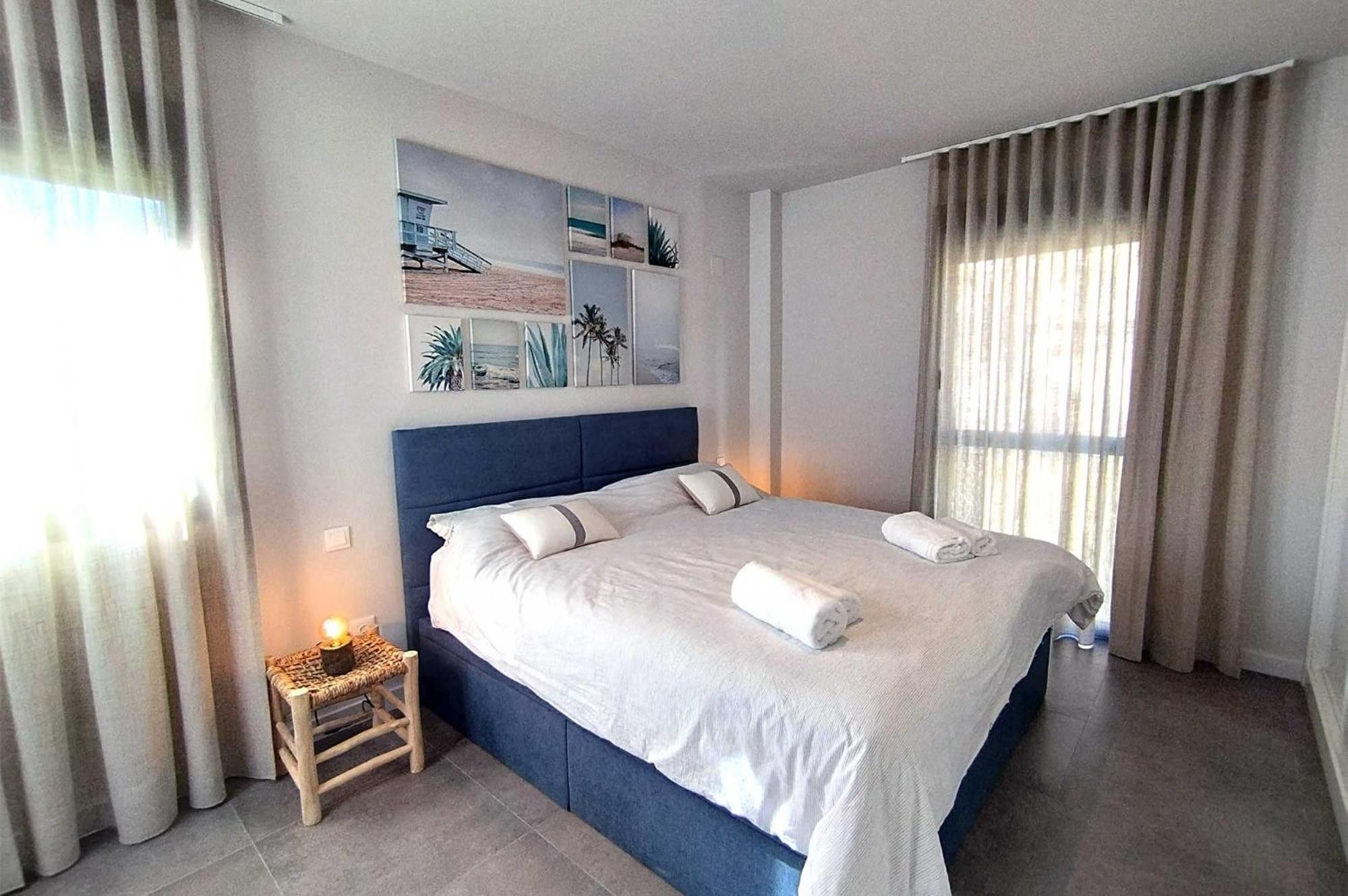 A hotel room with a large bed, a small bedside table with a lamp, and a wall with framed artwork.