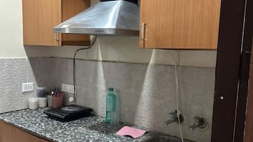 A kitchen with a stainless steel range hood, a granite countertop, a sink, and wooden cabinets.