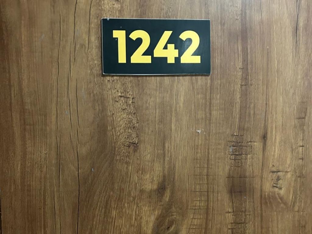 A wooden door with a black and yellow number sign indicating room number 1242.