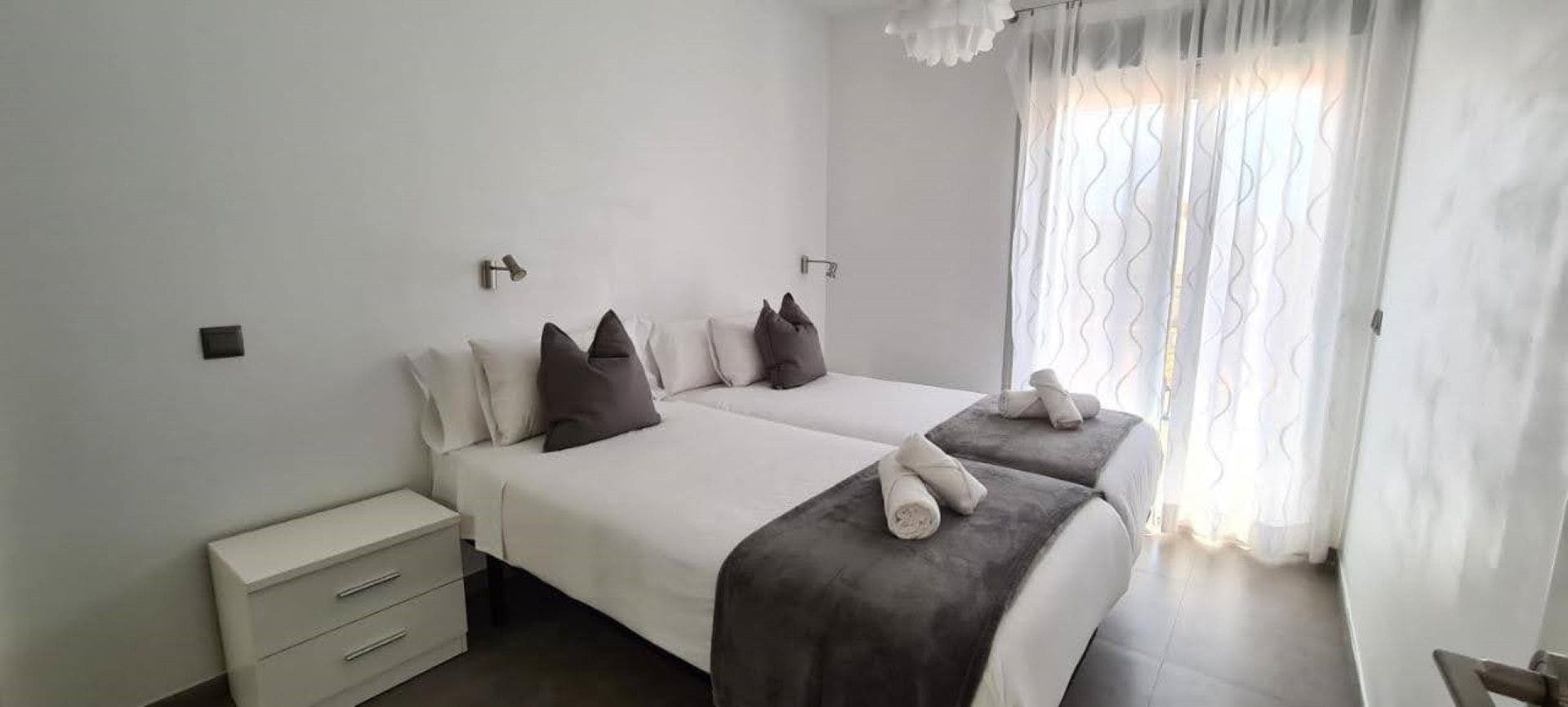 Habitación de hotel con dos camas, una mesita de noche y una ventana con cortinas.