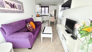 A modern living room with a purple sofa, a white coffee table, and a flat-screen TV. - La Cruz 8 Apartament SilHouse (Nerja)