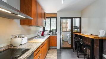 Una cocina compacta con estufa integrada, un lavamanos y una cafetera.