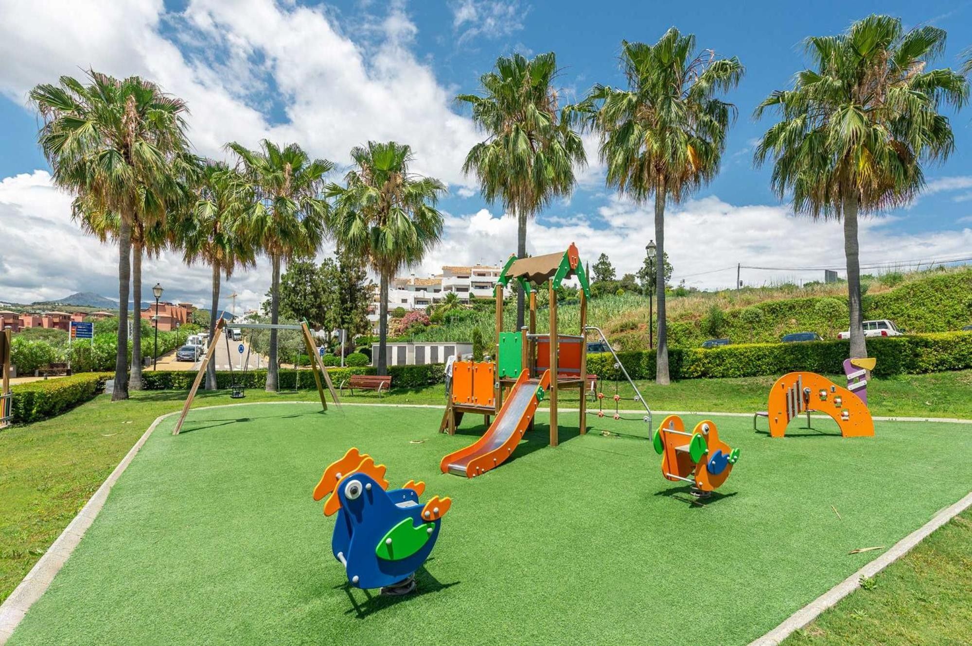 A playground with a slide, climbing structures, and a blue and orange play figure.