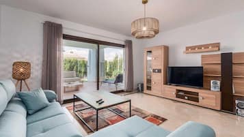 En moderne stue med sofa, sofabord, fjernsyn og skab.