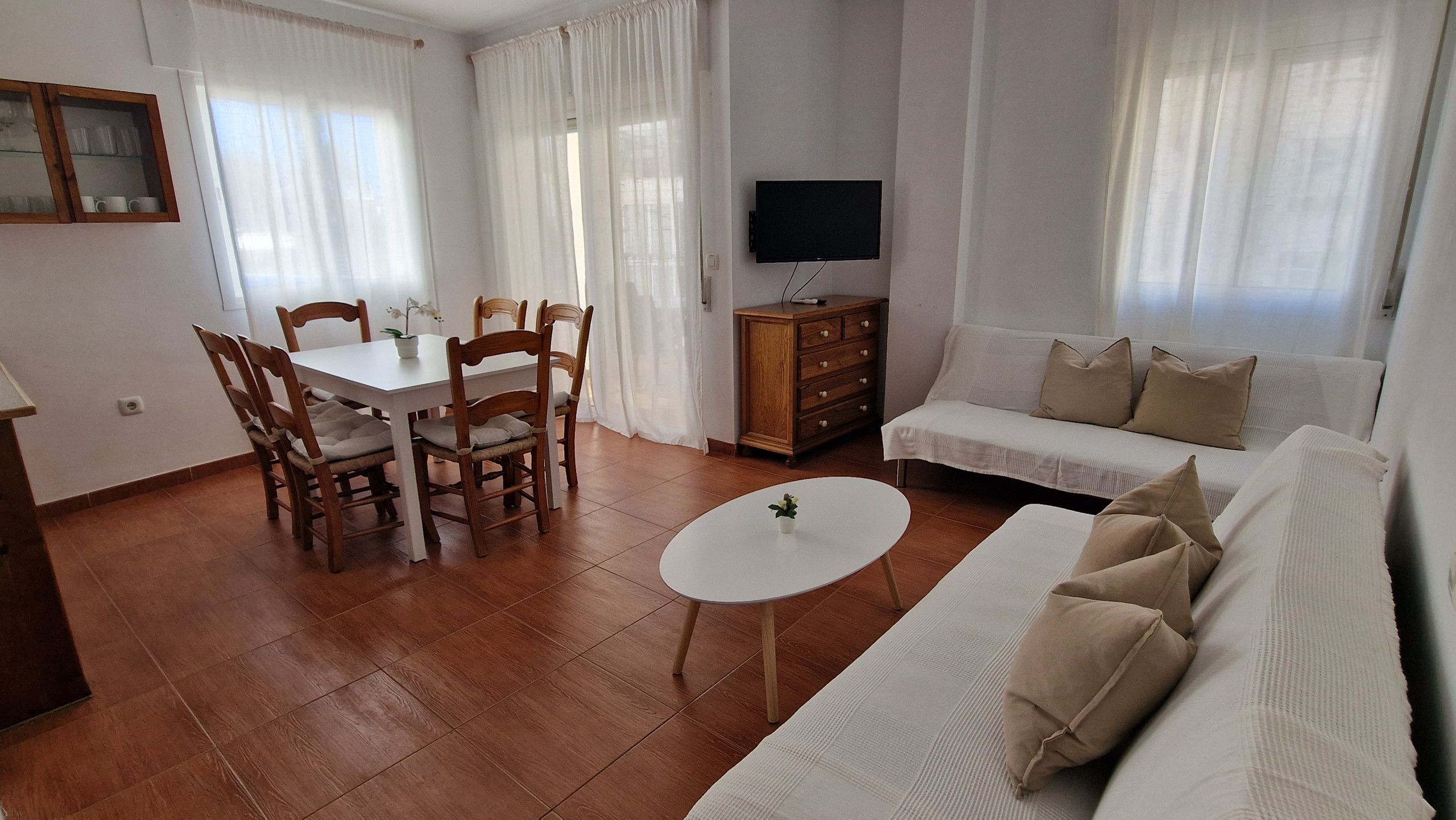 A living room with a dining area, a sofa, a TV, and a small table.