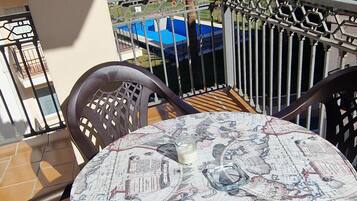 A round table with a world map tablecloth, two chairs, and a view of mountains and a body of water.