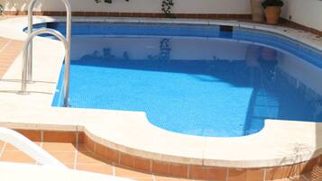 A swimming pool with a metal ladder and a tiled edge.