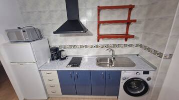 A compact kitchen with a sink, a coffee maker, a toaster, a microwave, and a washing machine.