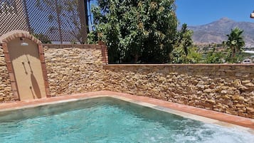 Ein Schwimmbecken mit einer Steinmauer und einer Holzpergola.