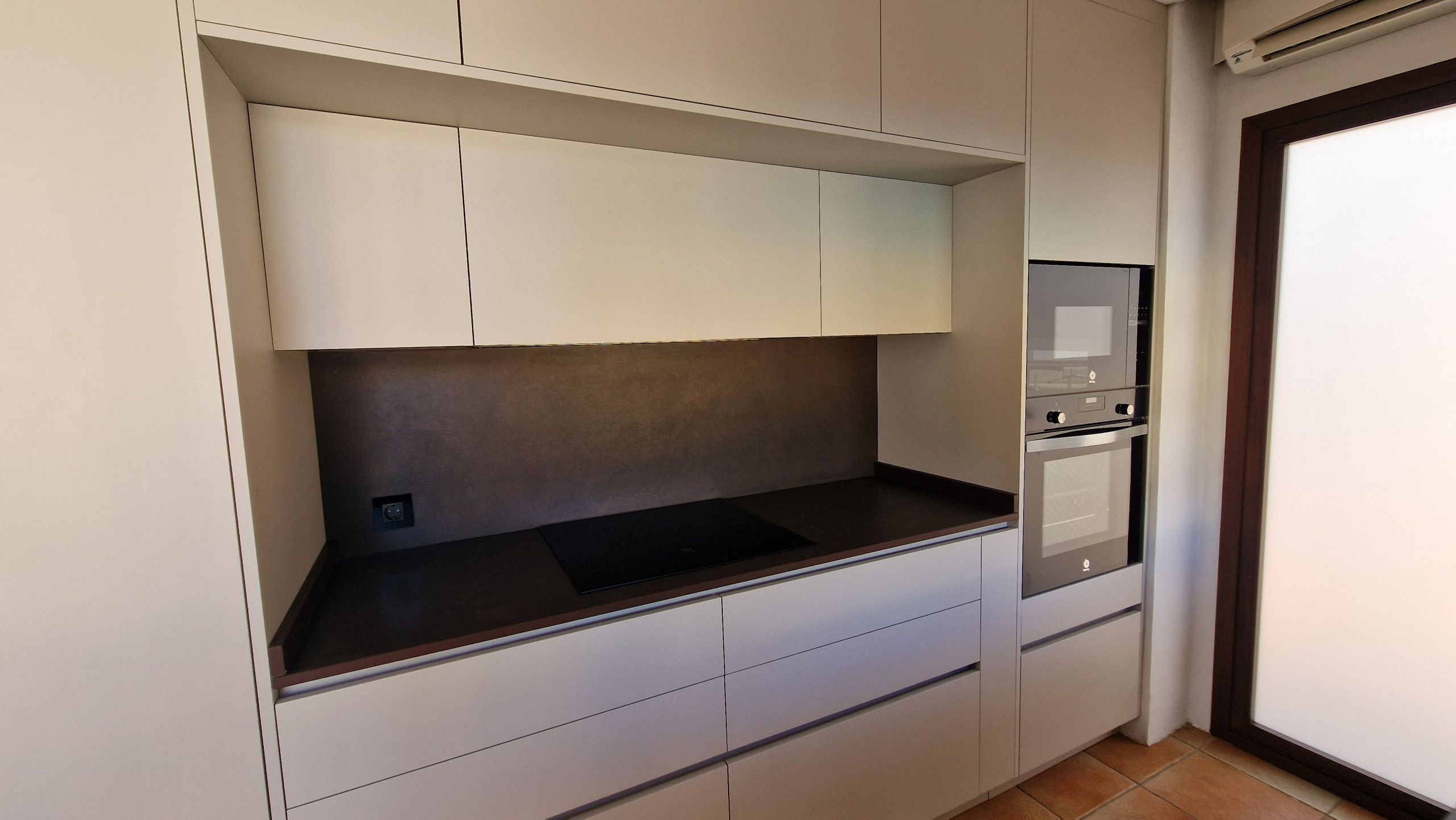 A kitchen with a built-in microwave, oven, and a small sink.