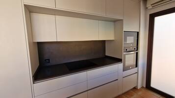 A kitchen with a built-in microwave, oven, and a small sink.