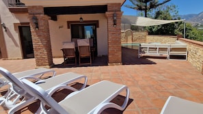 Un patio con sillones blancos, una mesa y un muro de piedra.